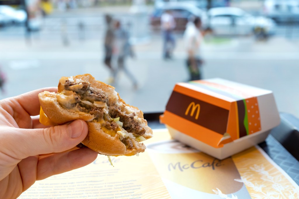Man enjoying a Big Mac burger at a McDonald's restaurant by the window in Minsk, Belarus, 2022