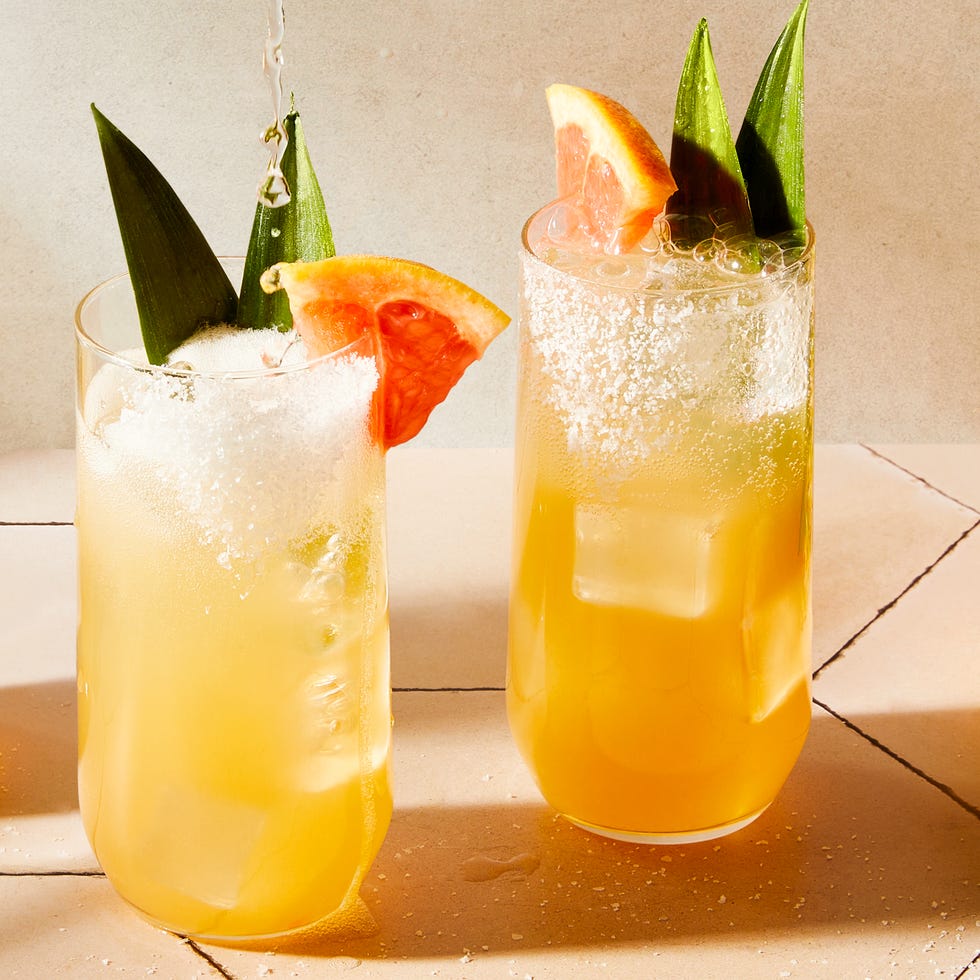 Piña Paloma glasses filled with grapefruit juice, pineapple juice, tequila, and soda water garnished with a grapefruit wedge, pineapple leaves, and a salted rim