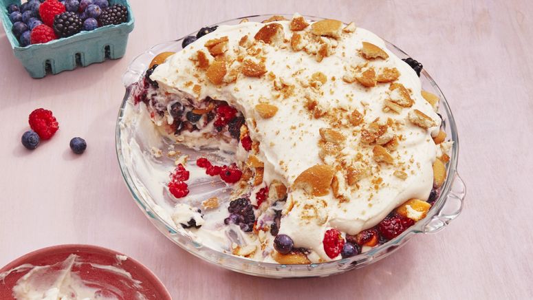 Pie plate filled with layers of mixed berries and lush vanilla whipped cream topped with shattered vanilla wafers.