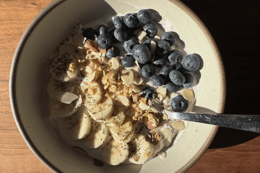 Just in Time for June: Two New Lazy Girl High-Protein Salads (Topped with Chips!) - 8 High-protein yogurt bowl topped with banana slices, blueberries, almonds, granola, and chia seeds. A spoon rests in the bowl.