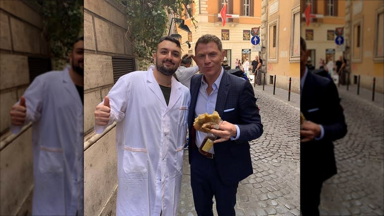 Bobby Flay holding sandwich, standing with man in Rome