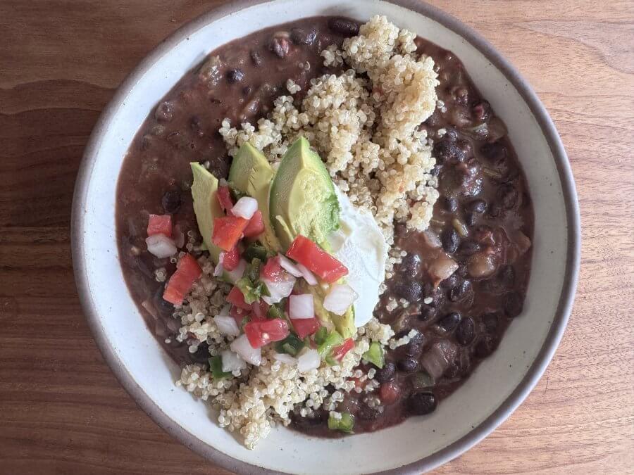 Just in Time for June: Two New Lazy Girl High-Protein Salads (Topped with Chips!) - 10 A high-protein bowl of black bean soup, topped with quinoa, avocado slices, diced tomatoes, onions, and a dollop of sour cream.