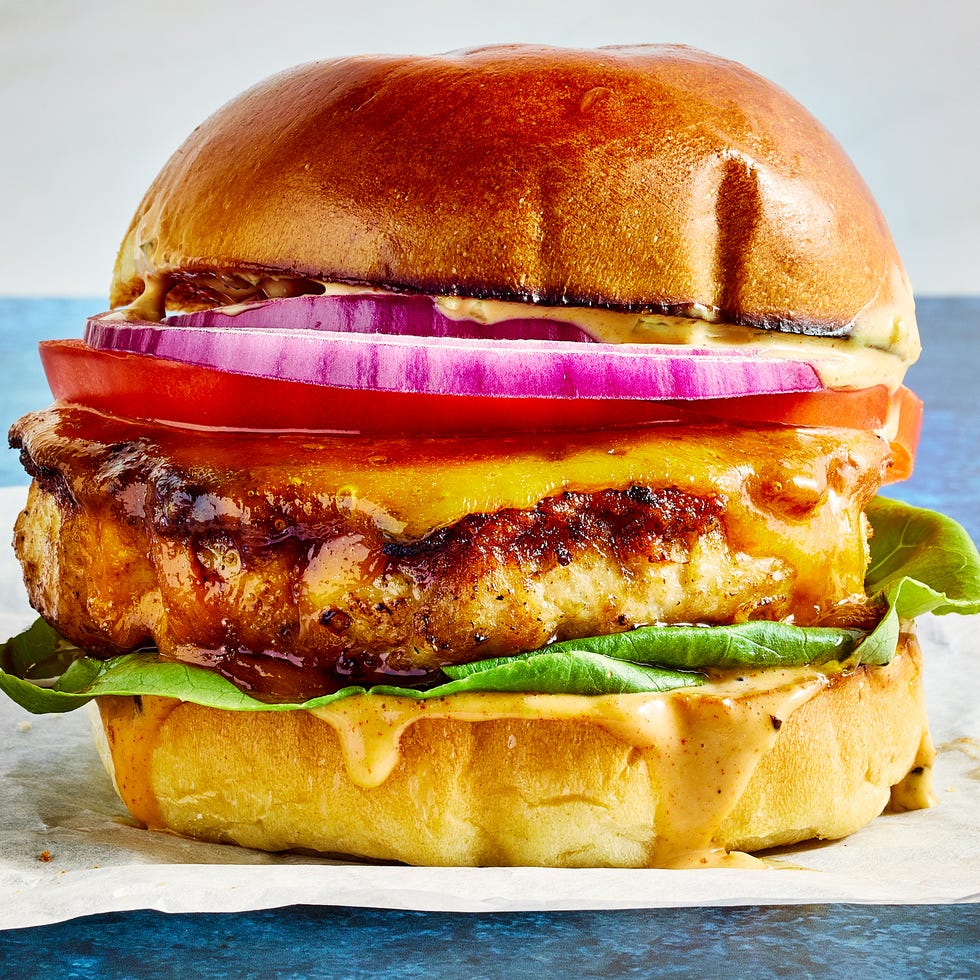 Chicken Burgers chicken burger topped with sauce, lettuce, sliced red onion, and tomato