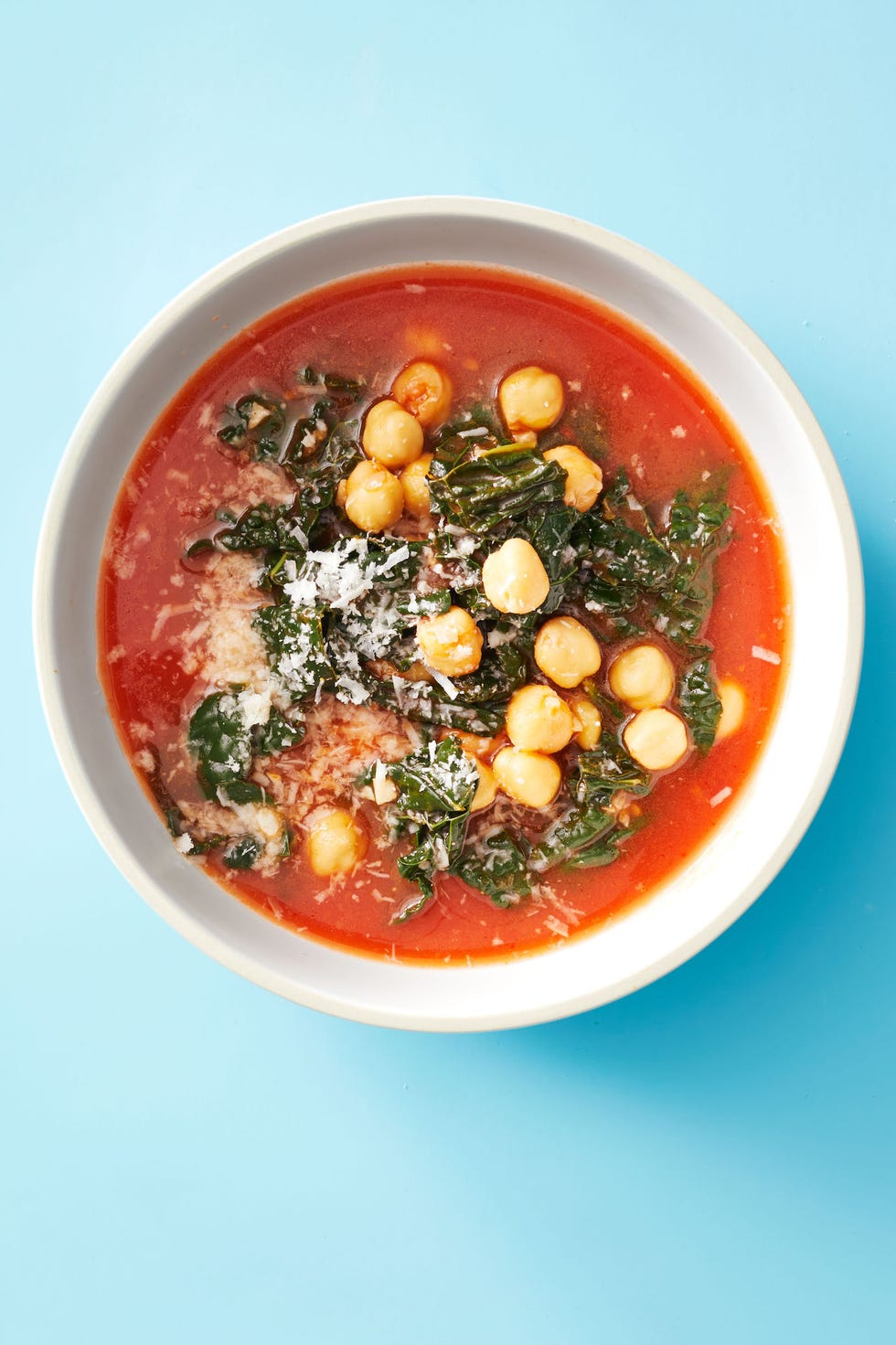 a bowl of kale and chickpea soup against a blue background