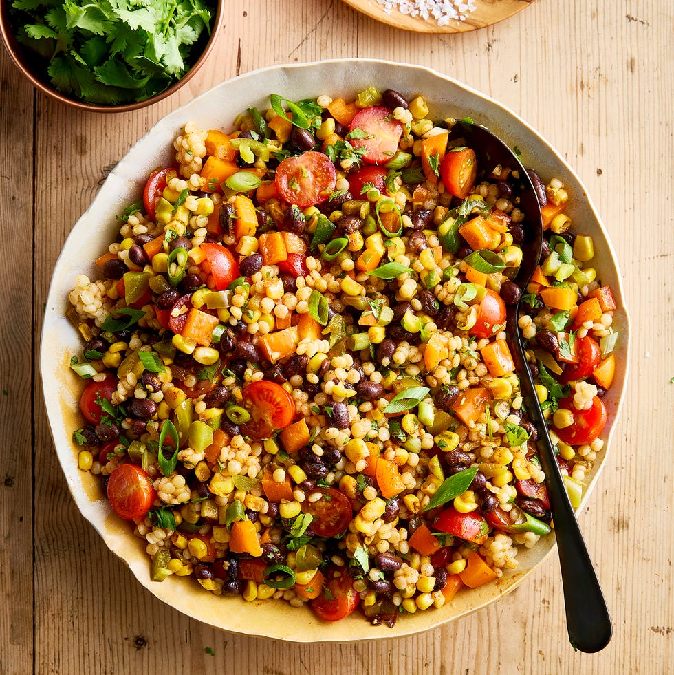Cowboy Caviar Couscous Salad a bowl with pearl couscous, black beans, corn, bell peppers, cherry tomatoes, scallions, cilantro, and pickled jalapenos
