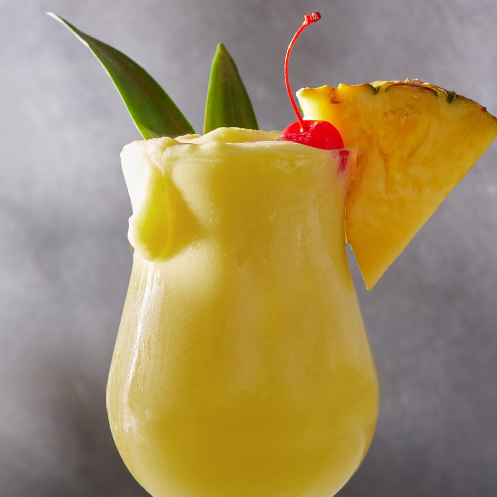 Piña Colada frozen pina colada cocktail with dark rum garnished with a maraschino cherry and pineapple wedge
