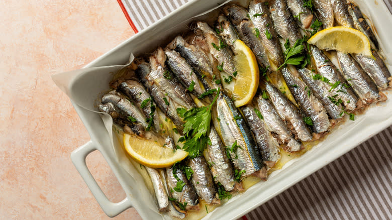 Whole small fish with lemons in baking dish