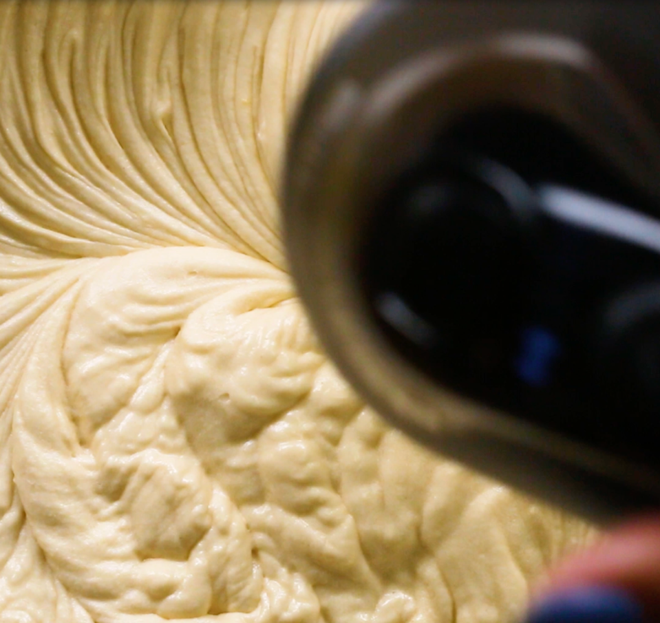 Close-up of dough being mixed by a stand mixer in a bowl, showcasing the texture and movement during the mixing process