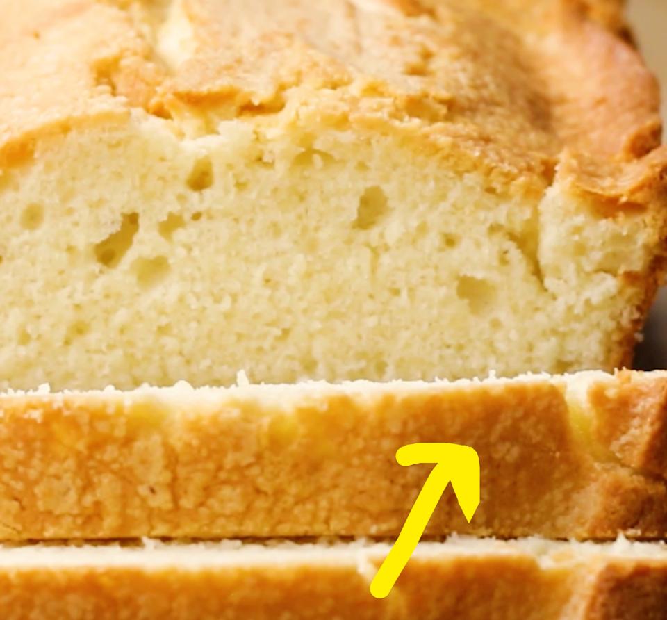 Sliced loaf of pound cake on a wooden surface, showing a rich, dense texture