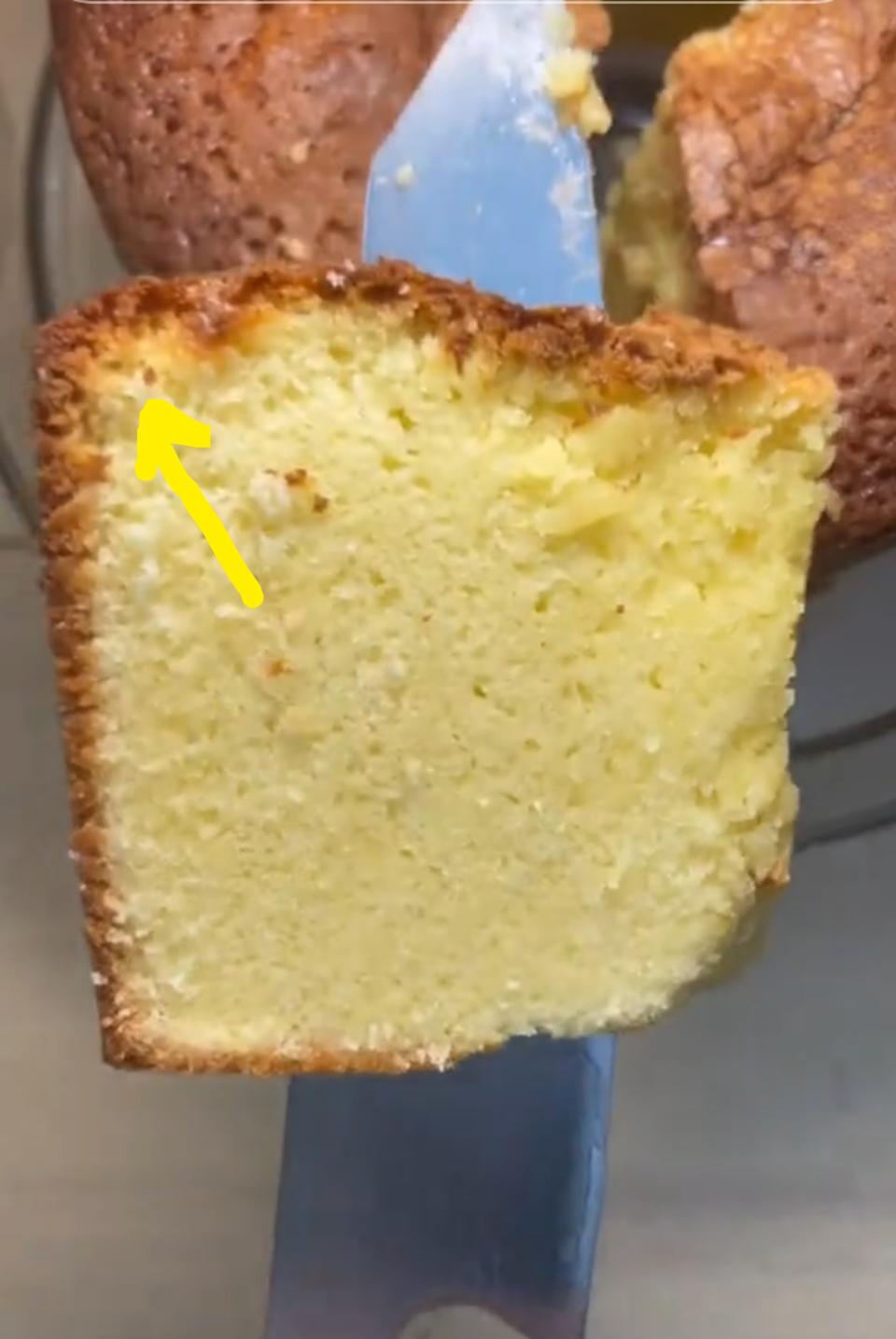 A slice of freshly baked cake with a golden crust and soft, fluffy interior sits on a metal spatula