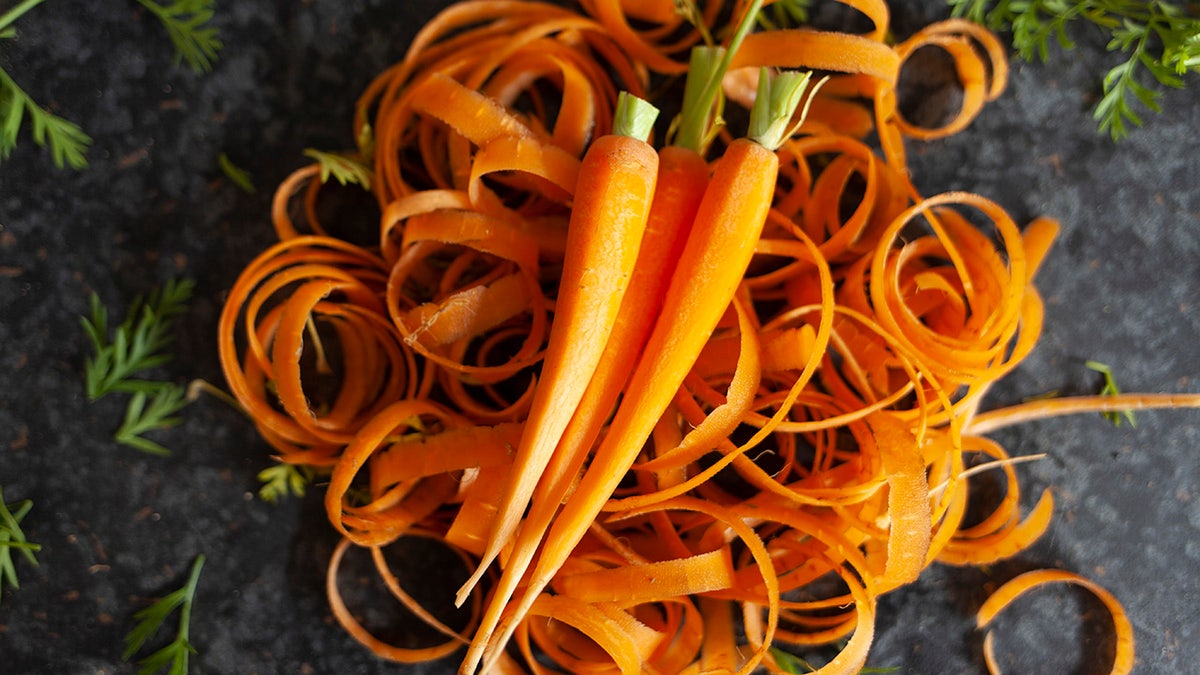 Carrots, freshly peeled, sit on a black table