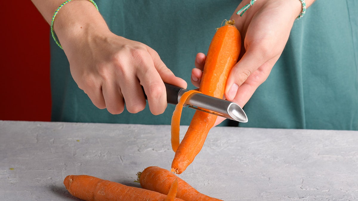 Hands peeling a large carrot
