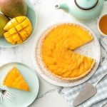 Plate with tasty mango pie and cup of tea on light background