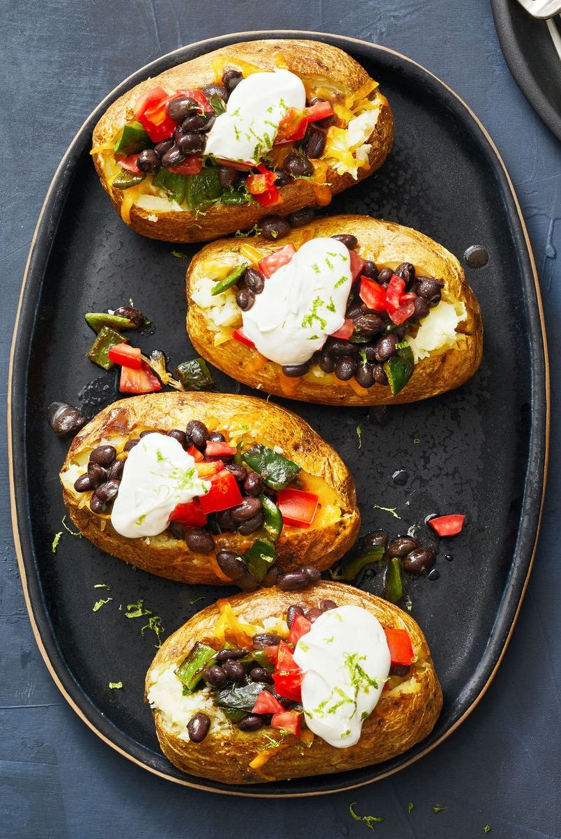 poblano and black bean loaded baked potatoes with dollops of cream on top