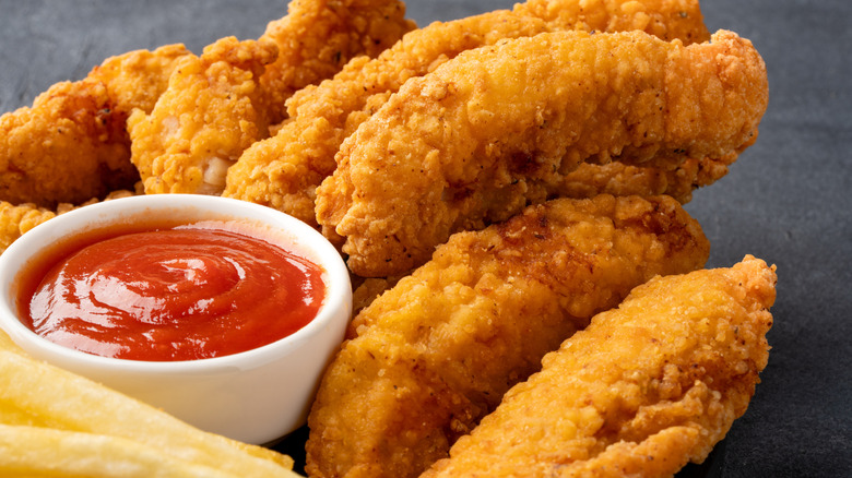Perfectly seasoned chicken tenders with a small bowl of ketchup on the side