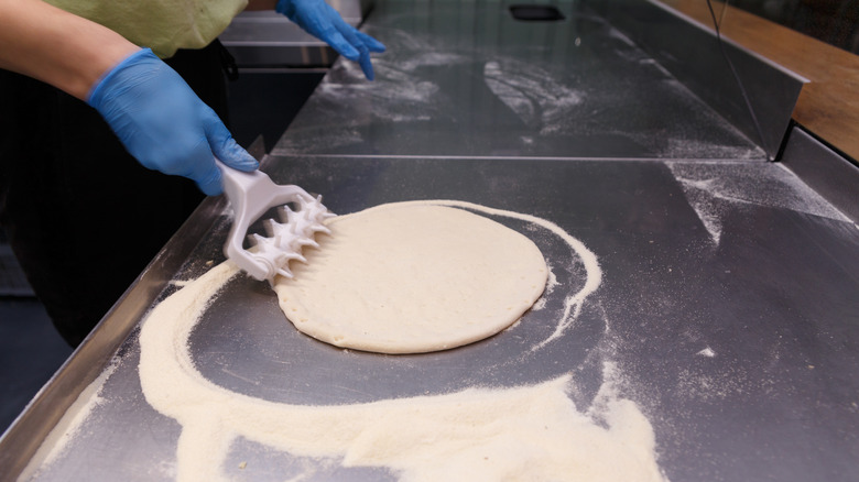 a chef docking a pizza with a dough docker