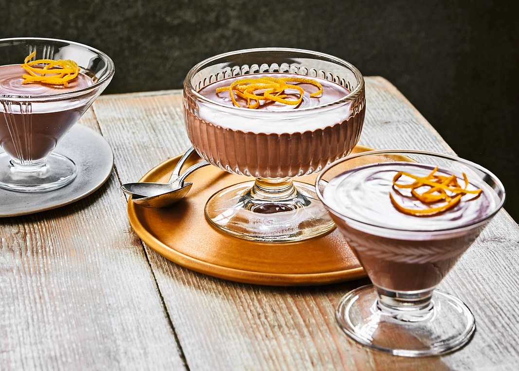 Three servings of chocolate mousse topped with orange zest.