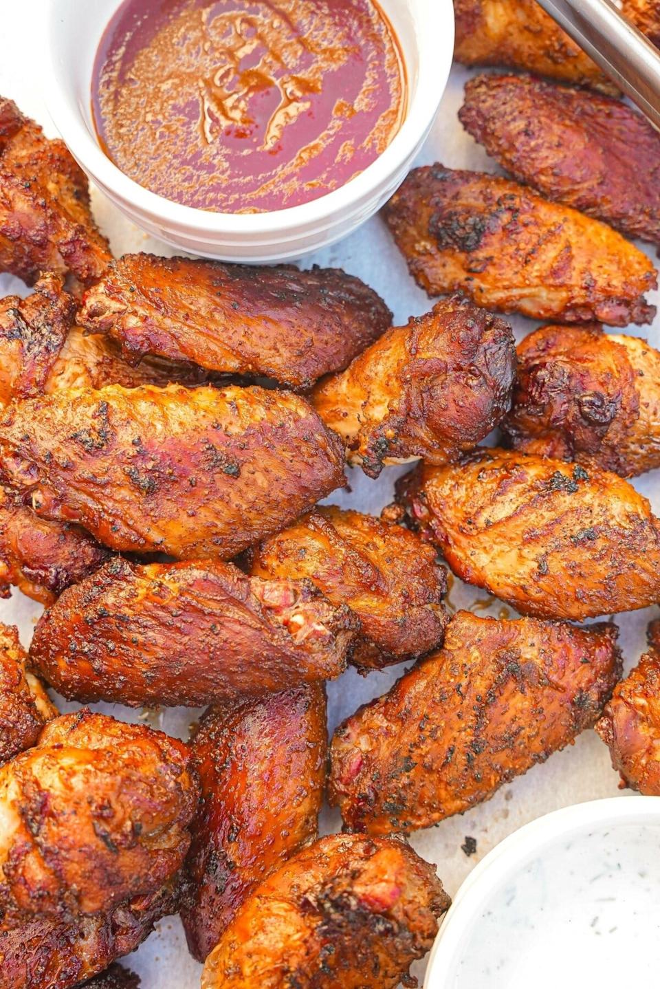 Grilled chicken wings with BBQ and ranch sauces on the side