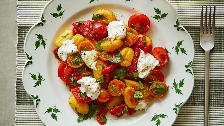 Crispy gnocchi tomatoes shredded mozzarella and torn basil leaves on a plate.