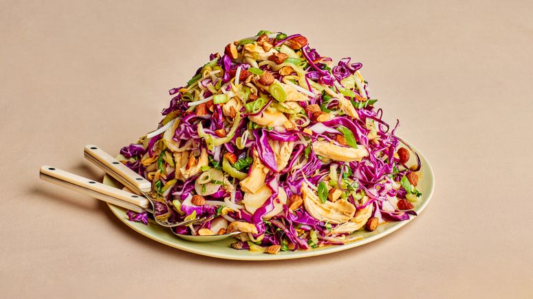 a mound of Purple cabbage salad with greens and chicken on a green plate