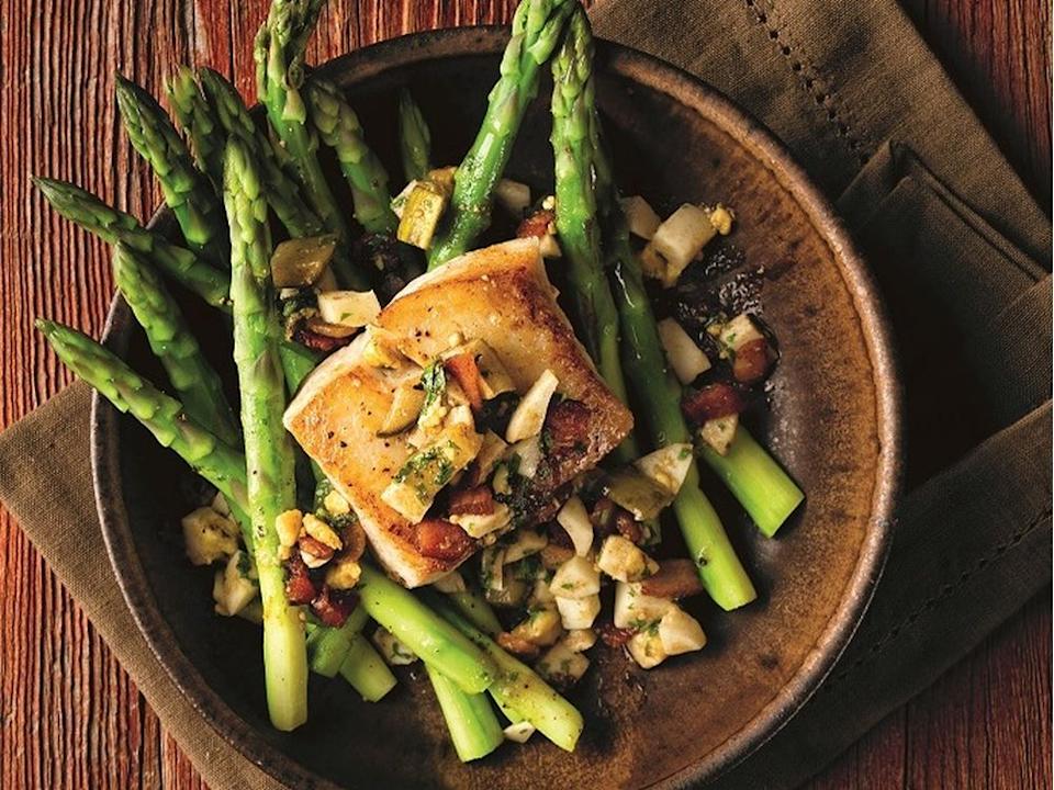 Chef Rod Butters arranges sautéed halibut atop asparagus that’s dressed with a mixture of chopped bacon, egg, pickle and parsley.