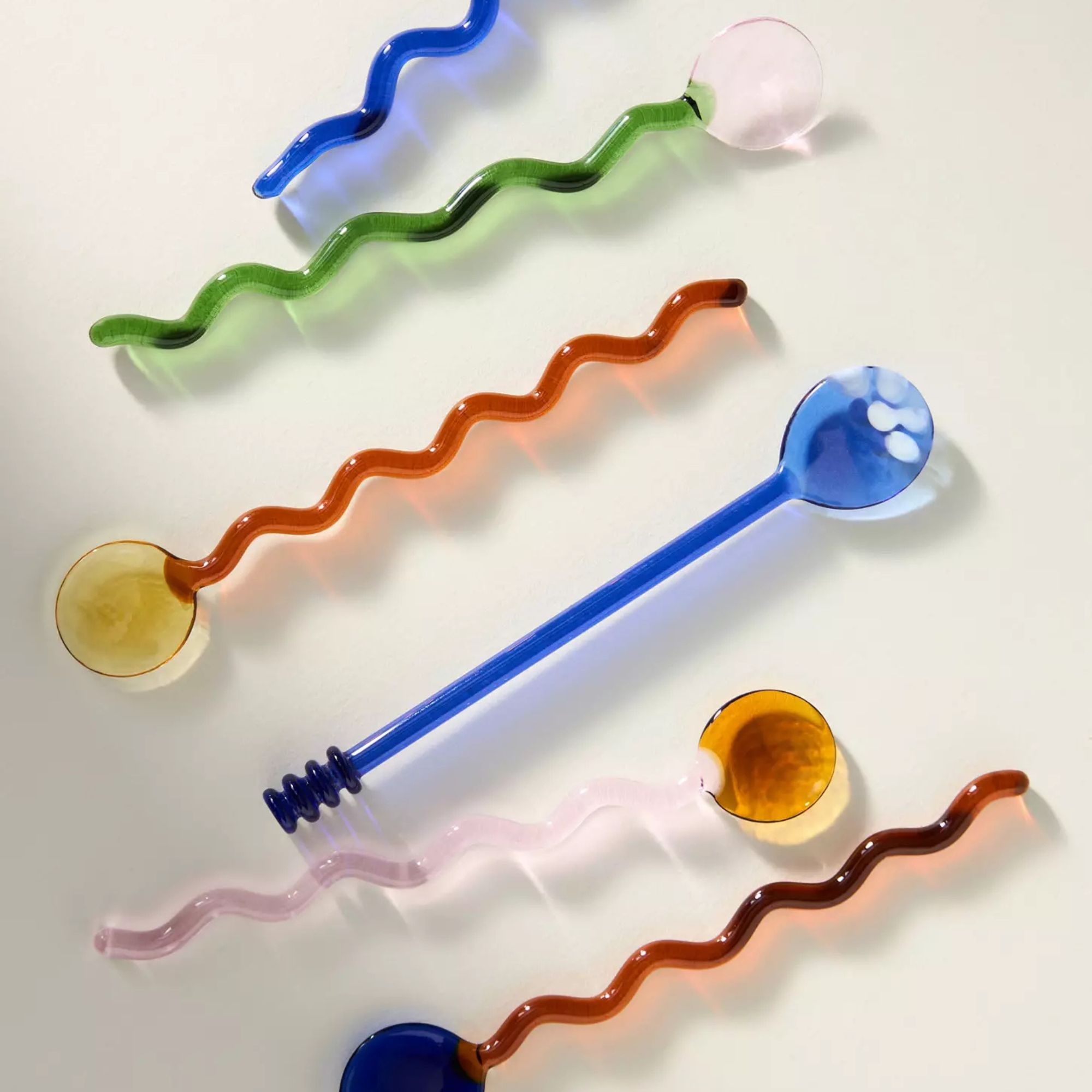 Glass spoons with wiggly handles in blue, pink, yellow and orange