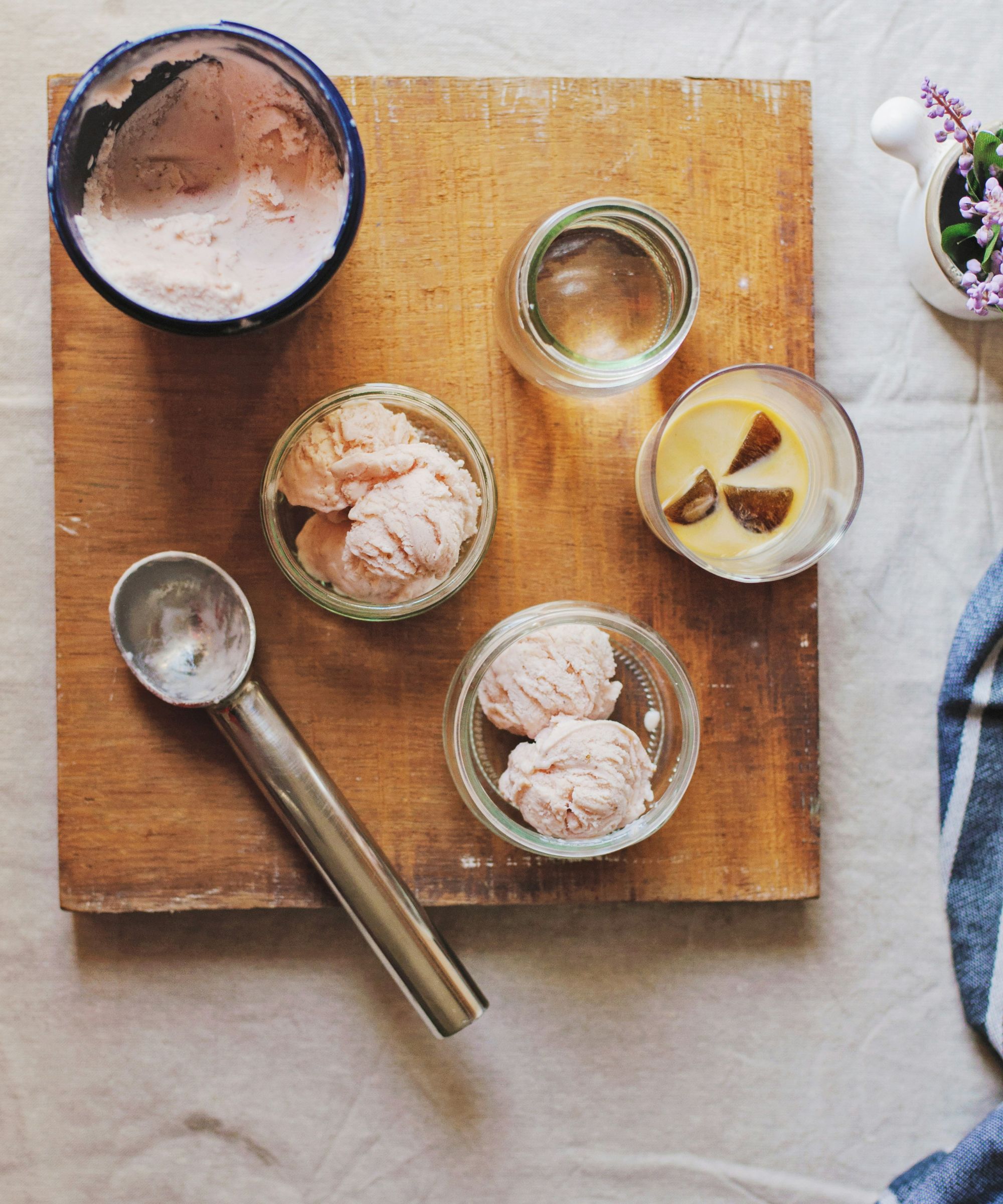 Aerial view of wooden board with ice cream scoop and bowls of strawberry ice cream