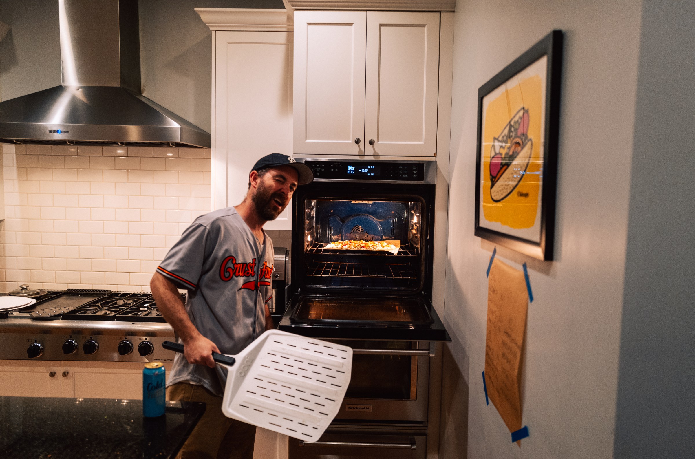 A smiling middle-aged man with a pizza in his oven.