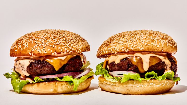 Two cheeseburgers on seeded buns with lettuce red onion and secret sauce.