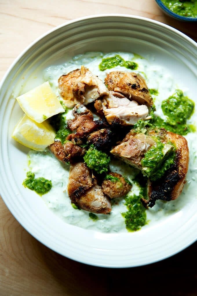 Grilled chicken with green sauce, served on creamy yogurt, garnished with lemon wedges