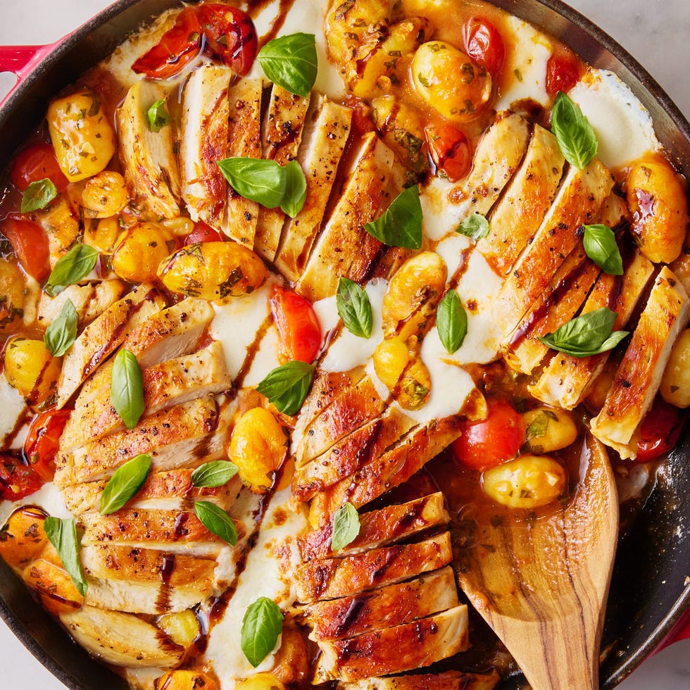 Caprese Chicken Gnocchi Skillet chicken with gnocchi, tomatoes, and cheese in a red skillet