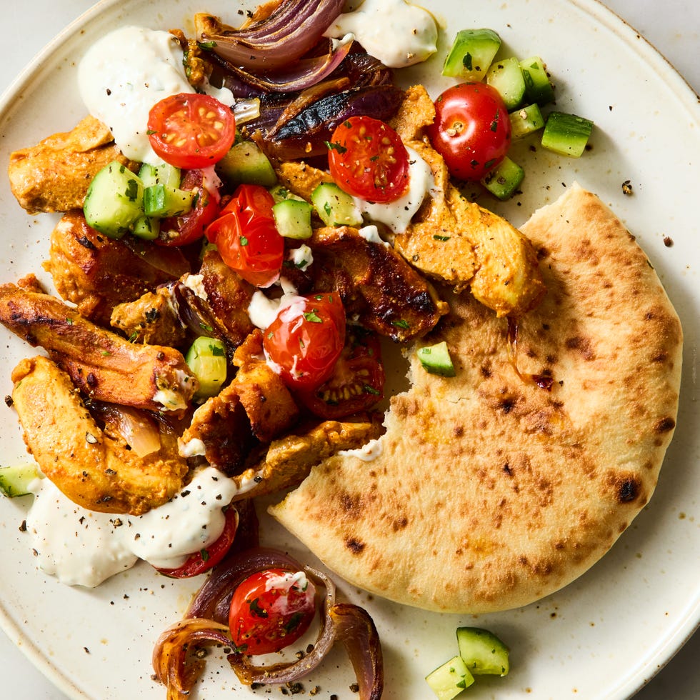 Chicken Shawarma Sheet Pan Dinner strips of chicken thigh are marinated in greek yogurt, cumin, coriander, and paprika, roasted on a sheet pan with red onion, then topped with a bright cucumber tomato salad and herby tahini yogurt dressing