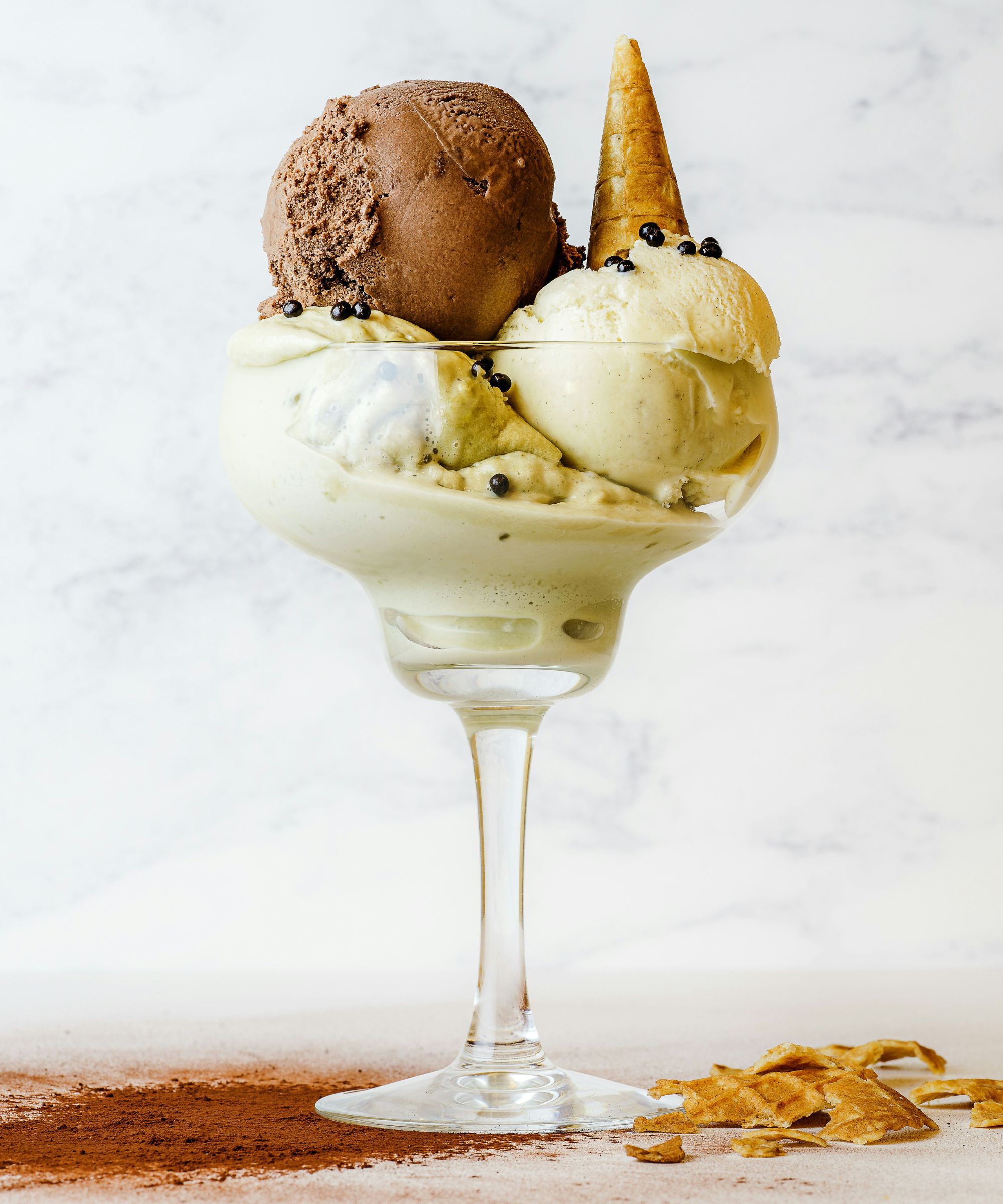 Ice cream sundae with vanilla and chocolate scoops, topped with a small waffle cone