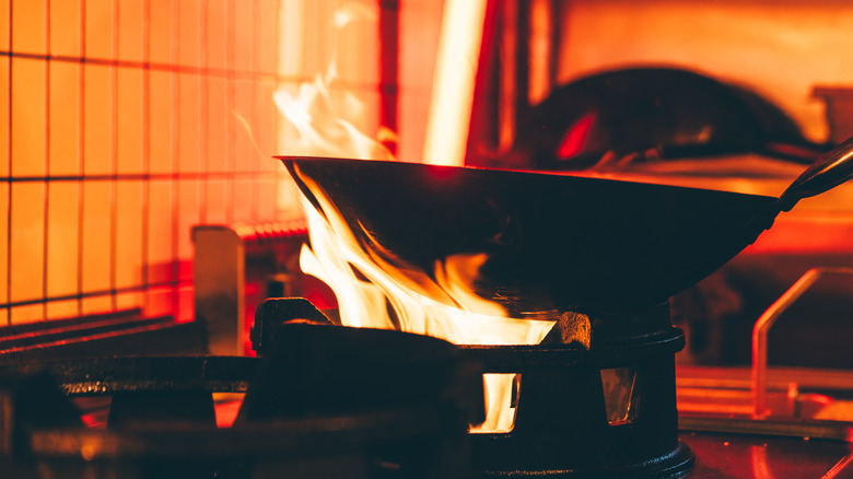 Wok being held over a strong flame