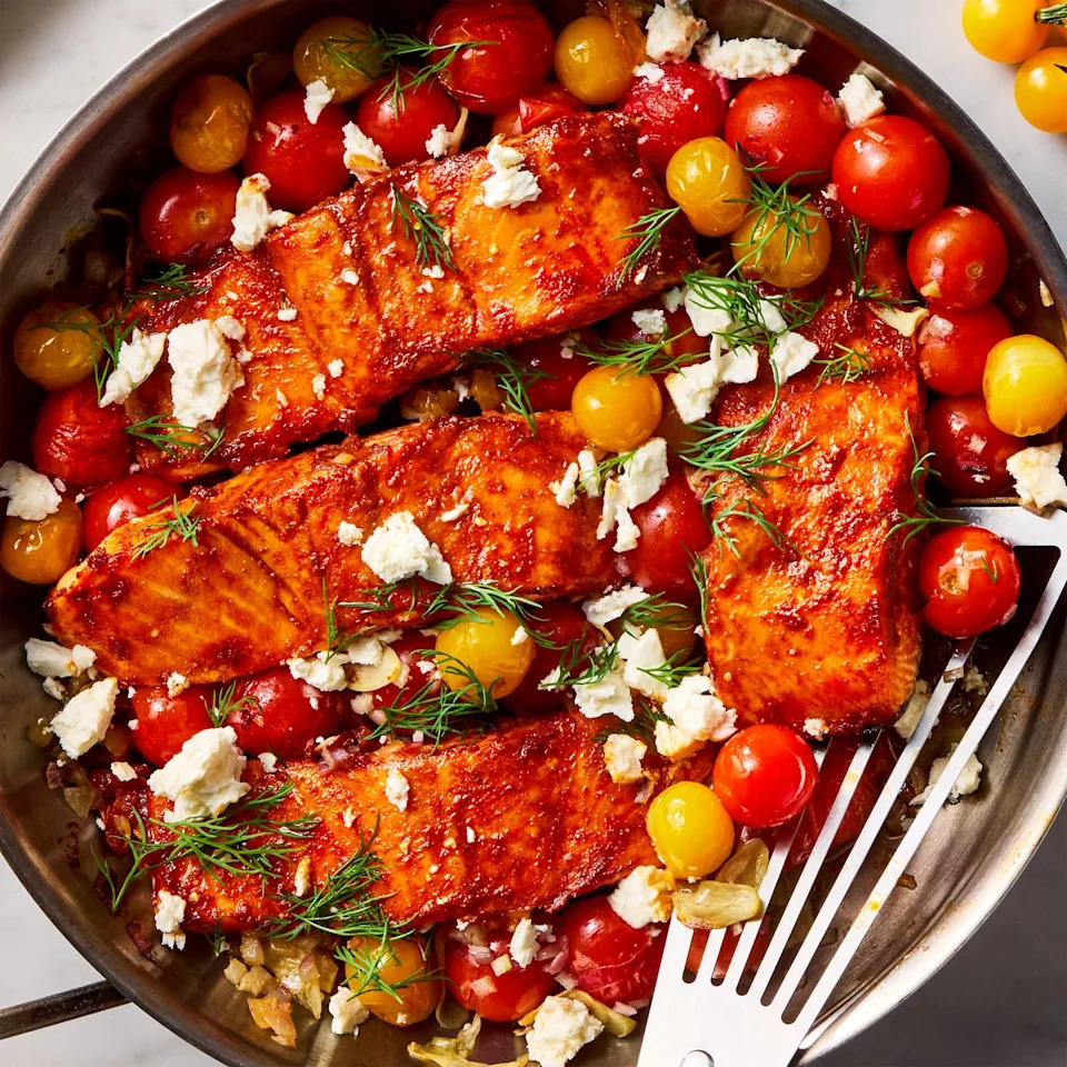 salmon filets are dusted with cumin and paprika, rubbed with spicy harissa paste, and roasted alongside cherry tomatoes, shallots, and garlic, then topped with fresh dill and creamy feta