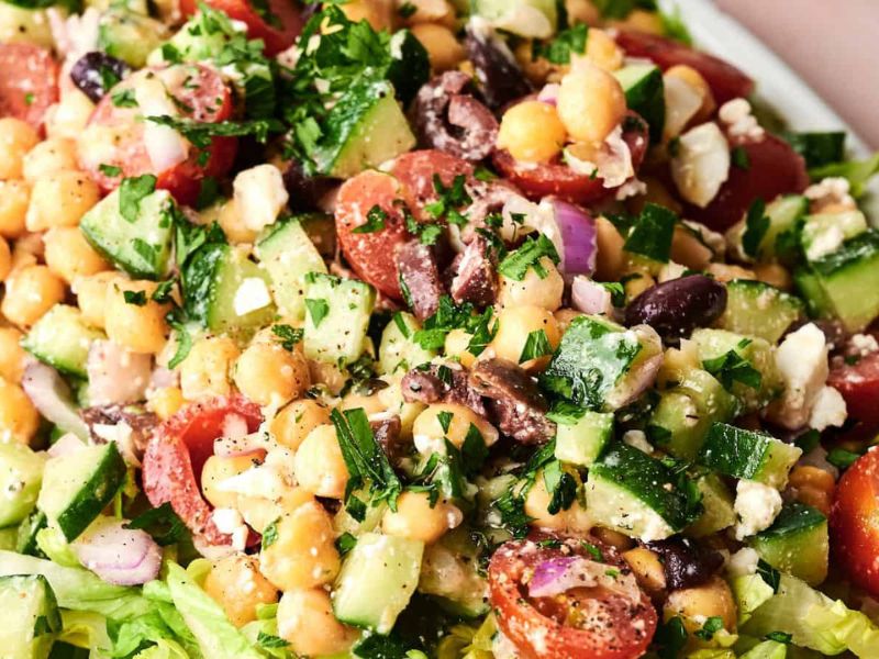 Chickpea salad with cherry tomatoes, cucumbers, red onions, olives, feta cheese, and chopped parsley.