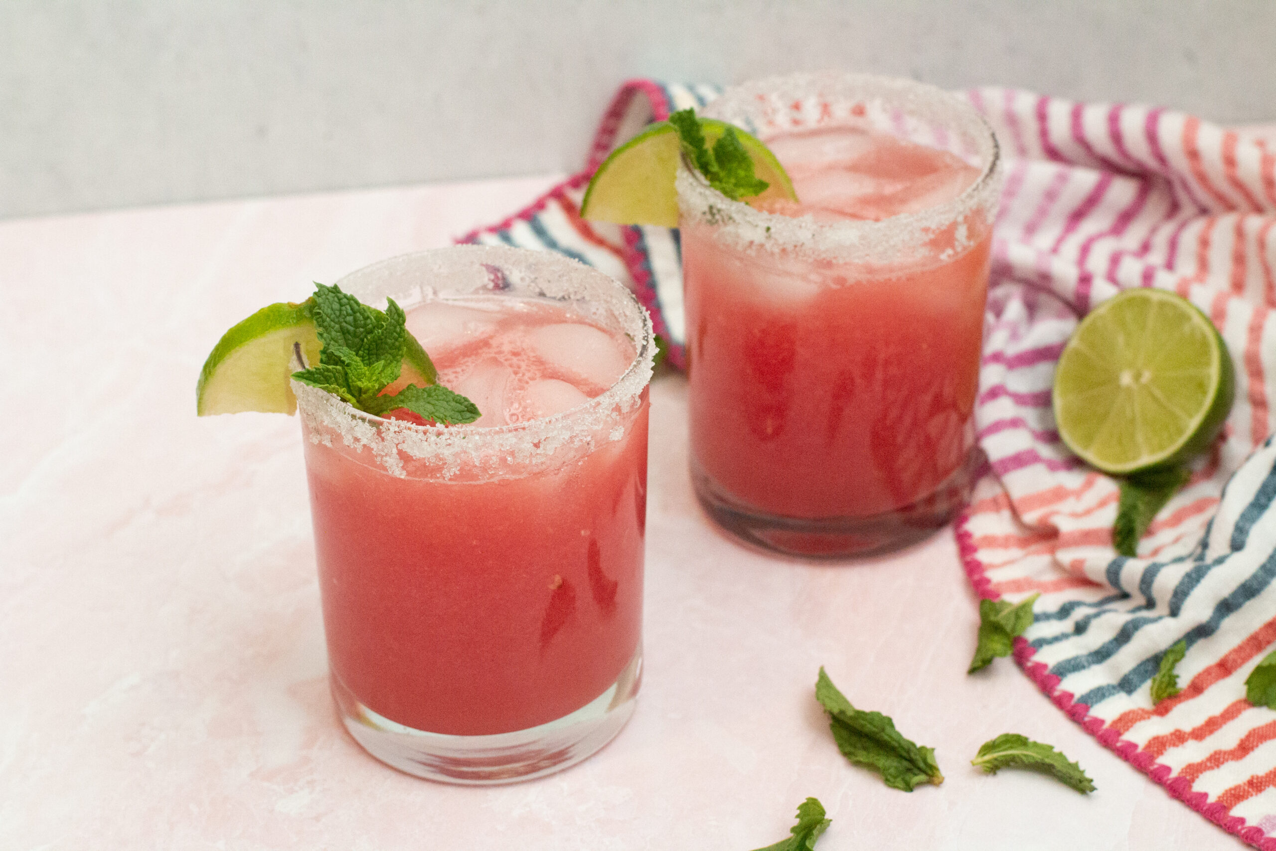 two watermelon margaritas with a striped towel and lime via Organic Authority
