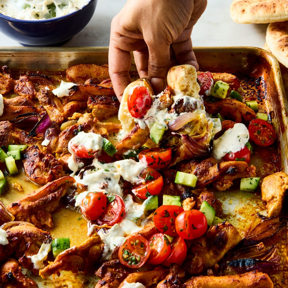 Chicken Shawarma Sheet Pan Dinner strips of chicken thigh are marinated in greek yogurt, cumin, coriander, and paprika, roasted on a sheet pan with red onion, then topped with a bright cucumber tomato salad and herby tahini yogurt dressing