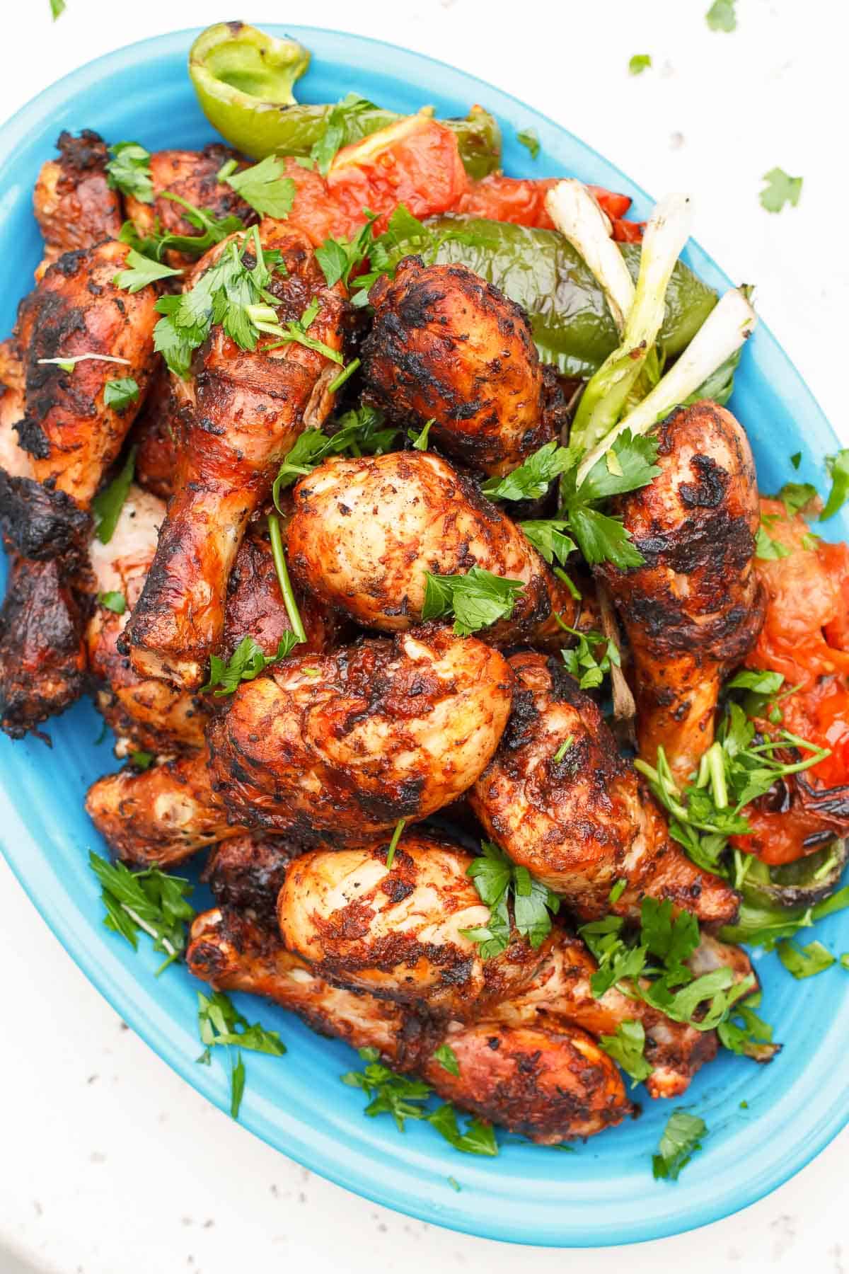 An overhead photo of grilled chicken drumsticks garnished with parsley on a serving platter.