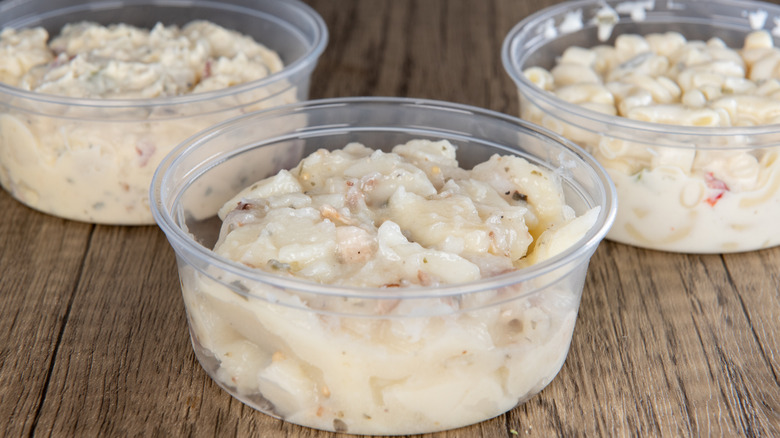 Various plastic containers of potato salad on a table