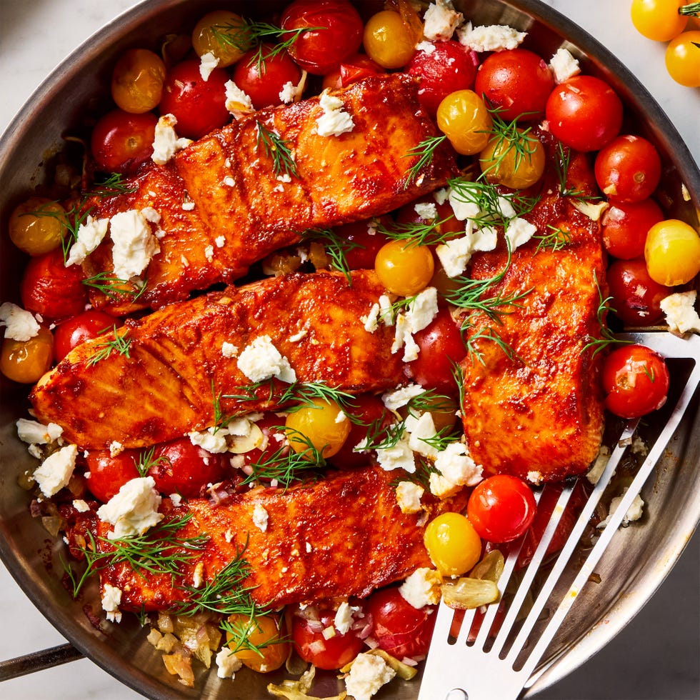 Summer Salmon Skillet salmon filets are dusted with cumin and paprika, rubbed with spicy harissa paste, and roasted alongside cherry tomatoes, shallots, and garlic, then topped with fresh dill and creamy feta
