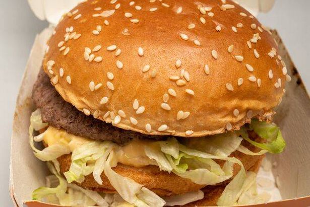 Closeup of sloppy assembled or cooked Bigmac burger taken away from McDonalds restaurant.