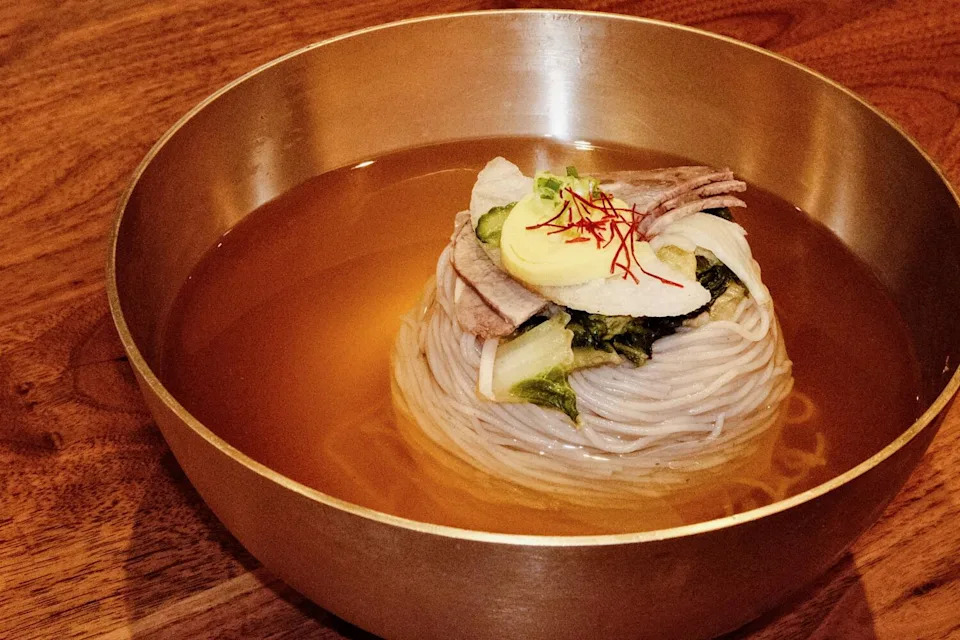 The original Pyongyang naengmyeon featuring noodles, beef and egg in a large gold bowl at Seogwan by Yellow Cow in Koreatown.
