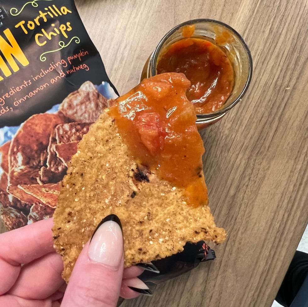 hand holding tortilla chip dipped in salsa