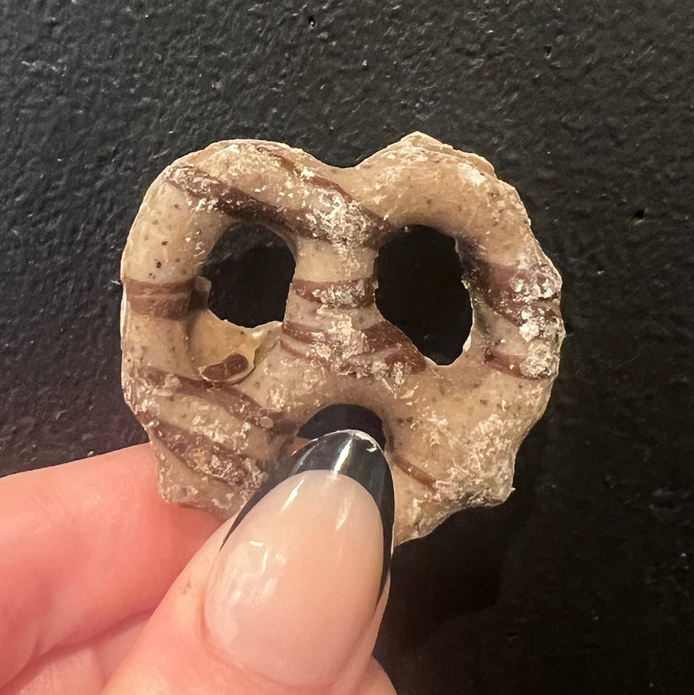 hand holding chocolate covered pretzel in front of black background
