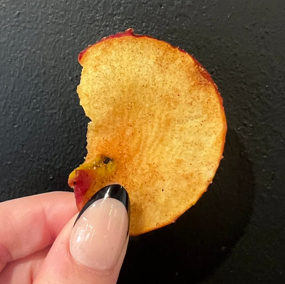 hand holding apple chip against black background