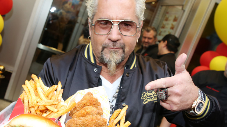 Guy Fieri pointing at a tray of fried food