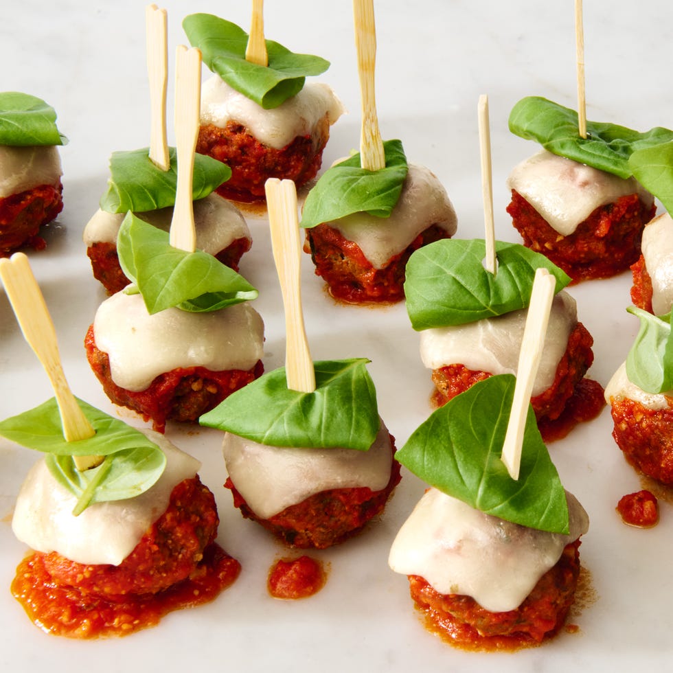 meatballs topped with tomato sauce, cheese, and basil on a skewer