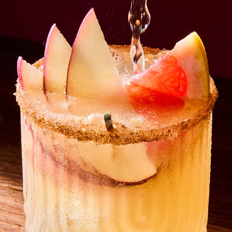 spiced apple paloma cocktail garnished with slices of apples and a grapefruit wedge