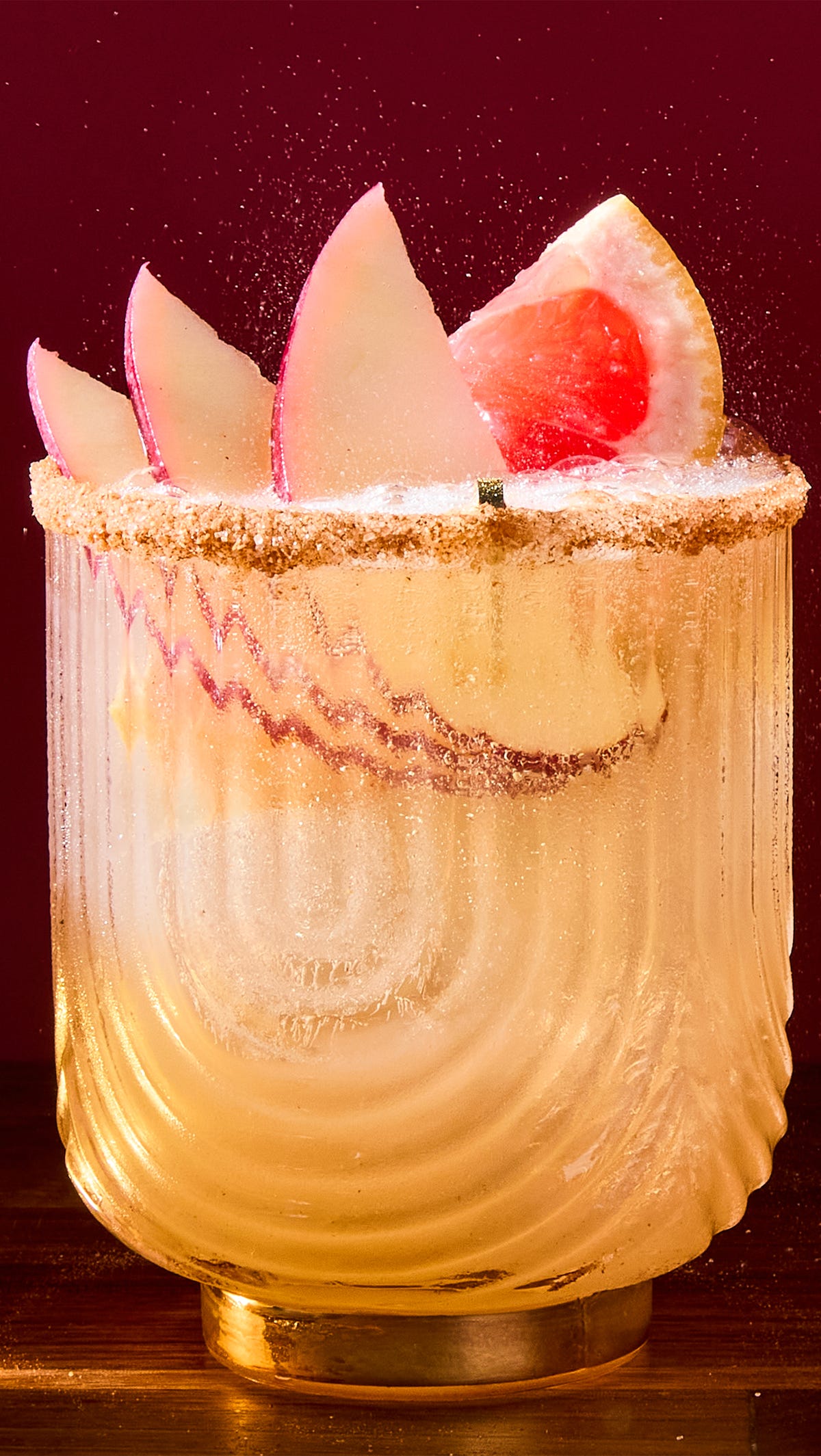 spiced apple paloma cocktail garnished with slices of apples and a grapefruit wedge